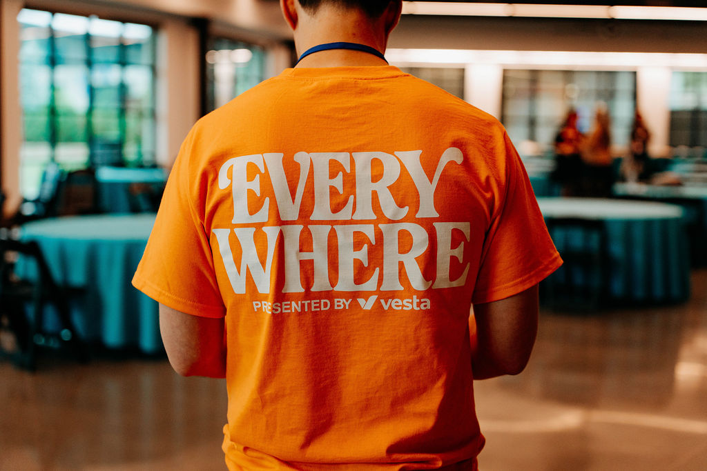 Volunteer in an orange EVERYWHERE presented by Vesta shirt