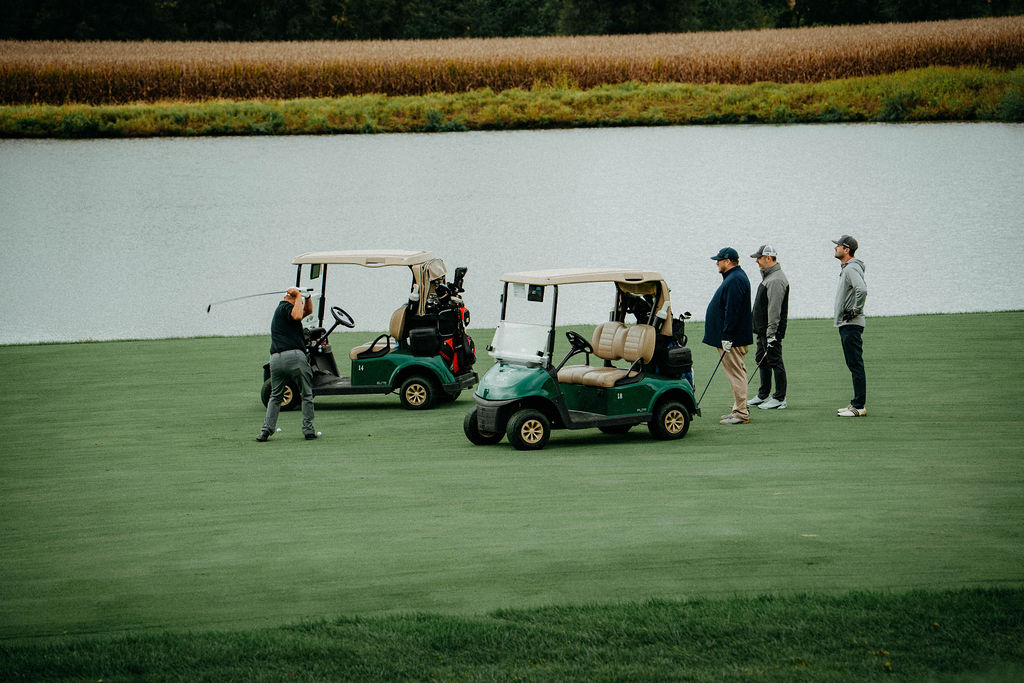 Golf carts and players by the pond