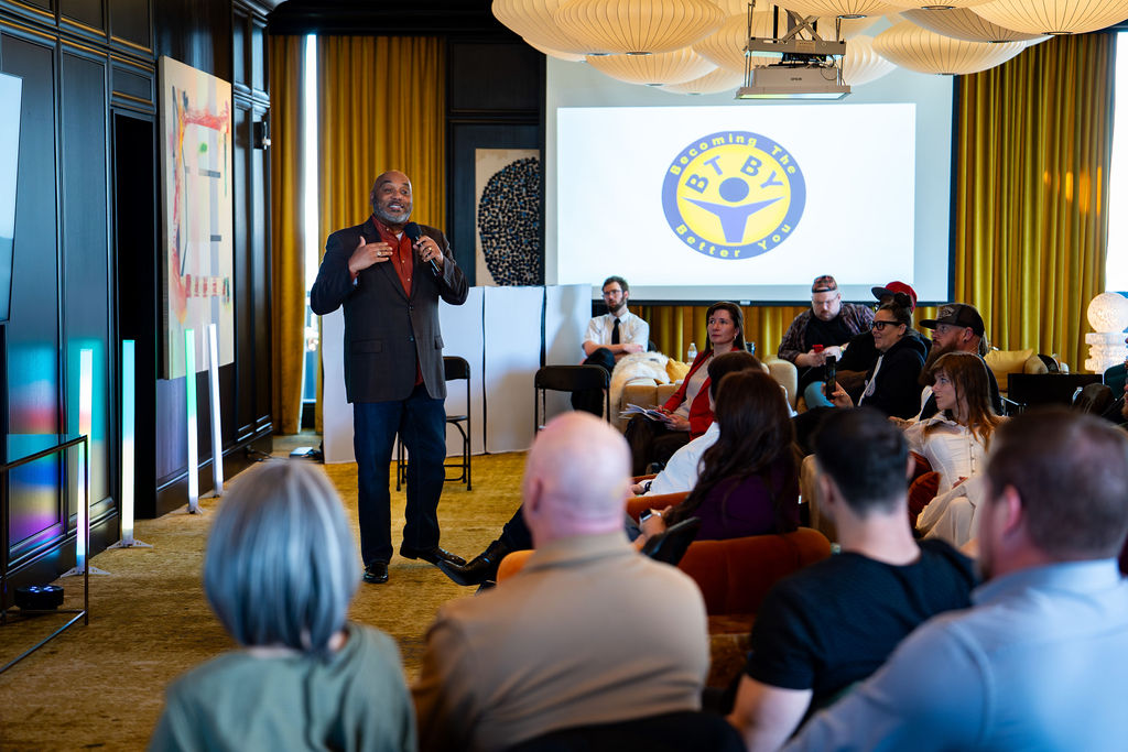 Speaker addressing the room in front of the BTBY logo on screen