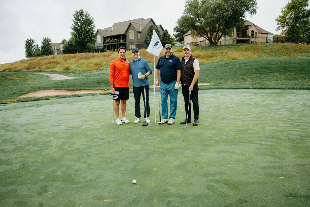Foursome posing by the flag on the green
